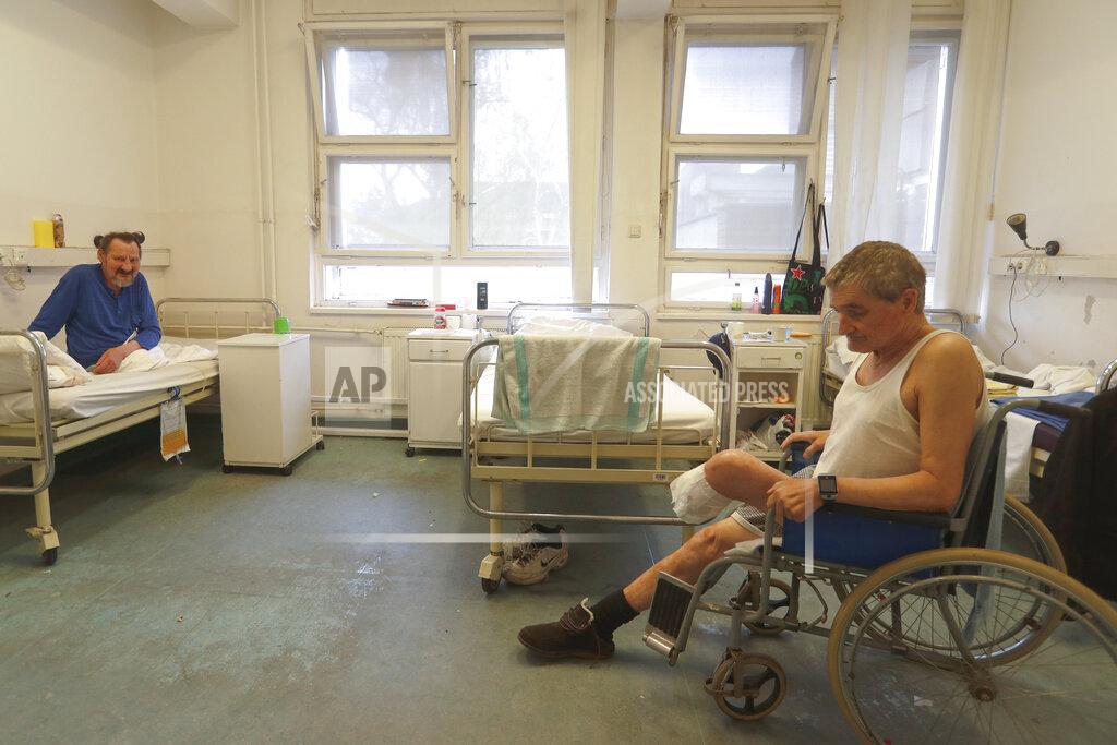 Laszlo Balogh Patients sit in a ward of the hospital for the homeless in Budapest, Hungary, Thursday, April 14, 2021. A bitter conflict has emerged between Hungary’s right-wing government and the liberal leadership of the country's capital city over a hospital for the homeless that may soon have to close. The Budapest hospital provides medical and social services and shelter to more than 1,000 people annually. But the Hungarian government has ordered it to vacate the state-owned building it occupies. Budapest's mayor says the eviction will risk the lives of the hospital's homeless patients as Hungary struggles with a deadly COVID-19 surge. (AP Photo/Laszlo Balogh)