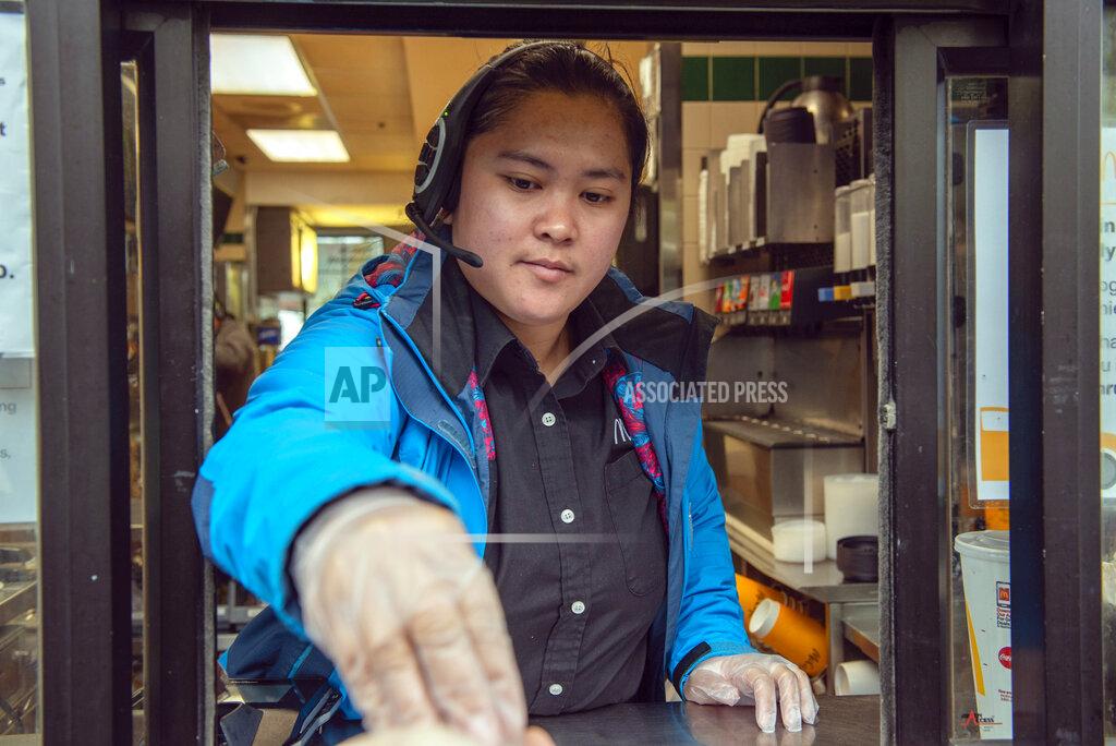 James Poulson Milagrose Sarmiento works the drive-thru window at McDonald's Restaurant in Sitka, Alaska, Friday, April 24, 2020. The restaurant closed the dining room, but has kept the drive-thru open during the coronavirus pandemic. (James Poulson/The Daily Sitka Sentinel via AP)