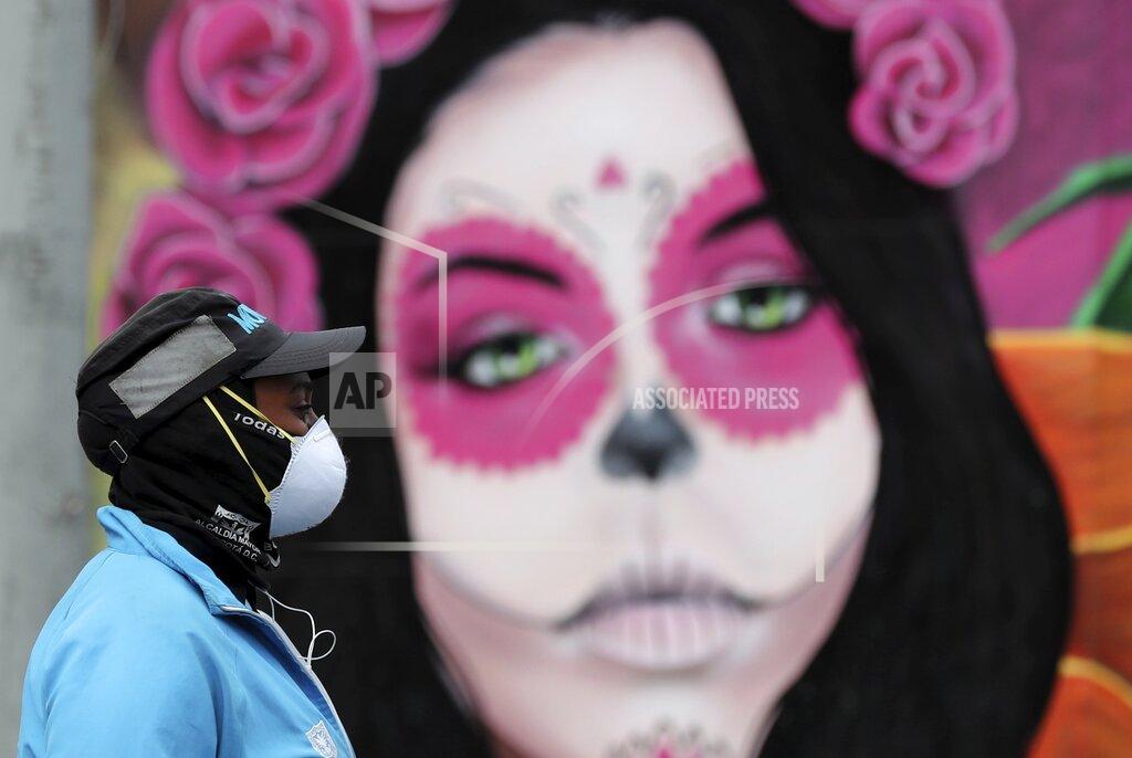 Fernando Vergara A woman wearing a face mask amid the spread of the new coronavirus walks past a Catrina mural in Bogota, Colombia, Thursday, May 21, 2020. (AP Photo/Fernando Vergara)