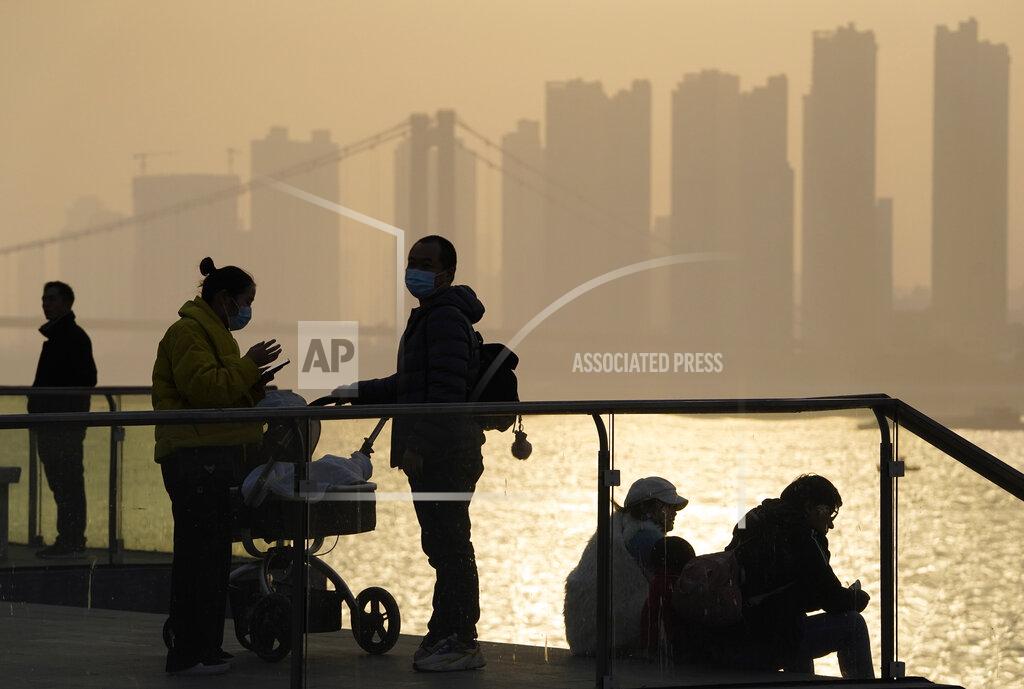 Ng Han Guan FILE - In this Jan. 15, 2021, file photo, residents enjoy the sunset along the riverbank in Wuhan in central China's Hubei province. Couples go on dates, families dine out at restaurants, shoppers flock to stores. Face masks aside, people are going about their daily life pretty much as before in the Chinese city that was first hit by the COVID-19 pandemic. (AP Photo/Ng Han Guan, File)