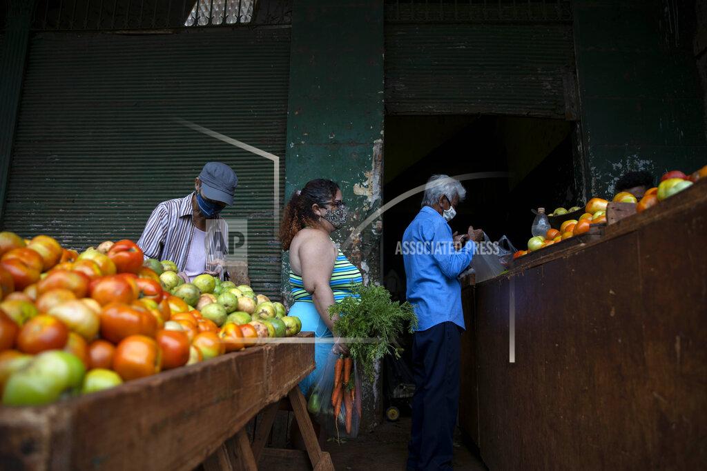 Yuliet Colon, center, waits to check-out at an agricultural market near her home, in Havana, Cuba, Friday, April 2, 2021. Colon is among several Cubans who, with more ingenuity than resources, help their compatriots cope with shortages exacerbated by the new coronavirus pandemic with Facebook posts of culinary creations designed around what they're actually likely to find at the market or with government rations. (AP Photo/Ramon Espinosa)