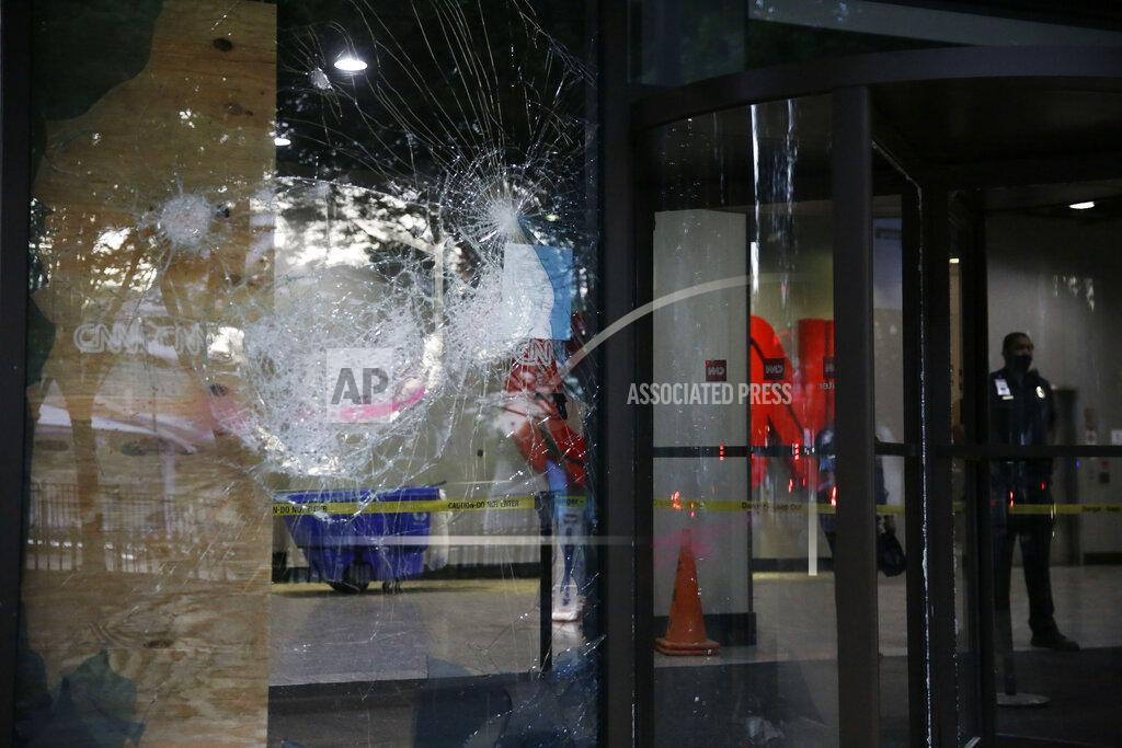 Brynn Anderson A security guard walks behind shattered glass at the CNN Center building in the aftermath of a demonstration against police violence on Saturday, May 30, 2020, in Atlanta. (AP Photo/Brynn Anderson)