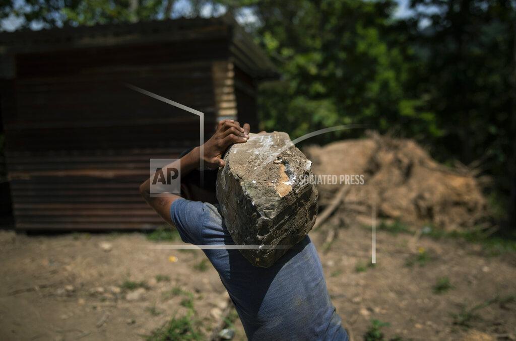 Rodrigo Abd A boy carries a rock at a construction site for new homes for the residents of La Reina, in Mission San Francisco de Asis, Honduras, Saturday, June 26, 2021. Hurricane Eta, then, Hurricane Iota, unleashed rains of biblical proportions in November 2020, causing a mudslide that obliterated the hillside community of La Reina. (AP Photo/Rodrigo Abd)