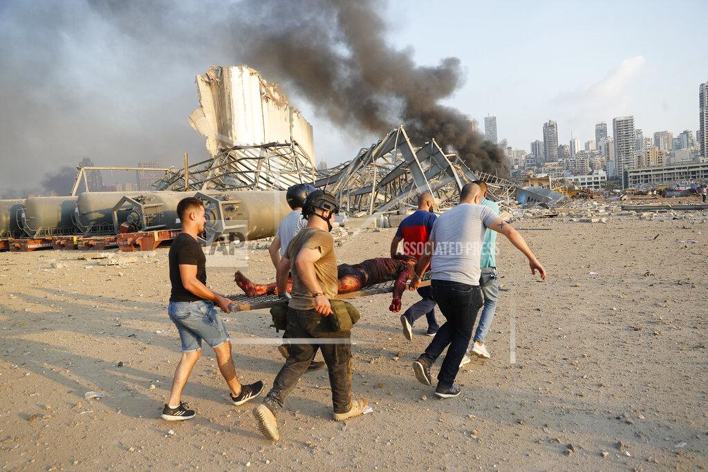 Hussein Malla Civilians carry a victim at the explosion scene that hit the seaport, in Beirut Lebanon, Tuesday, Aug. 4, 2020. Massive explosions rocked downtown Beirut on Tuesday, flattening much of the port, damaging buildings and blowing out windows and doors as a giant mushroom cloud rose above the capital. Witnesses saw many people injured by flying glass and debris. (AP Photo/Hussein Malla)