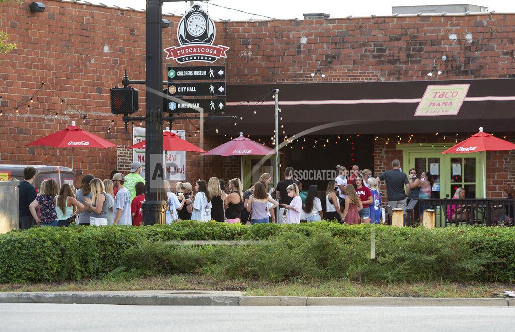 Vasha Hunt People line up outside to wait for limited access indoors to order food from Taco Mama, Saturday, Aug. 15, 2020, in Tuscaloosa, Ala. More than 20,000 students returned to campus at the University of Alabama for the first time since spring break, with numerous school and city codes in effect to limit the spread of COVID-19. (AP Photo/Vasha Hunt)