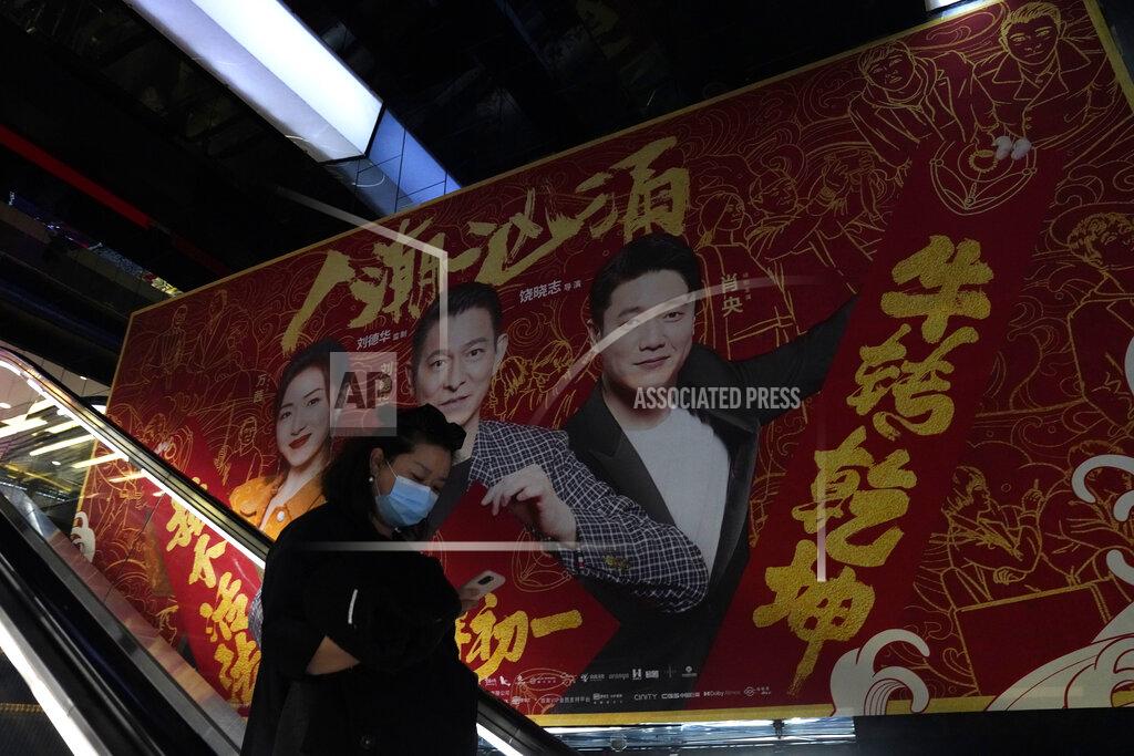 Ng Han Guan A woman wearing a mask passes by an ad for a movie in Beijing Thursday, Feb. 25, 2021. The state of the world's second largest economy takes precedence among the myriad issues presented by Premier Li Keqiang in his address at the National People's Congress opening session to take place on Friday, March 5. 2021. (AP Photo/Ng Han Guan)