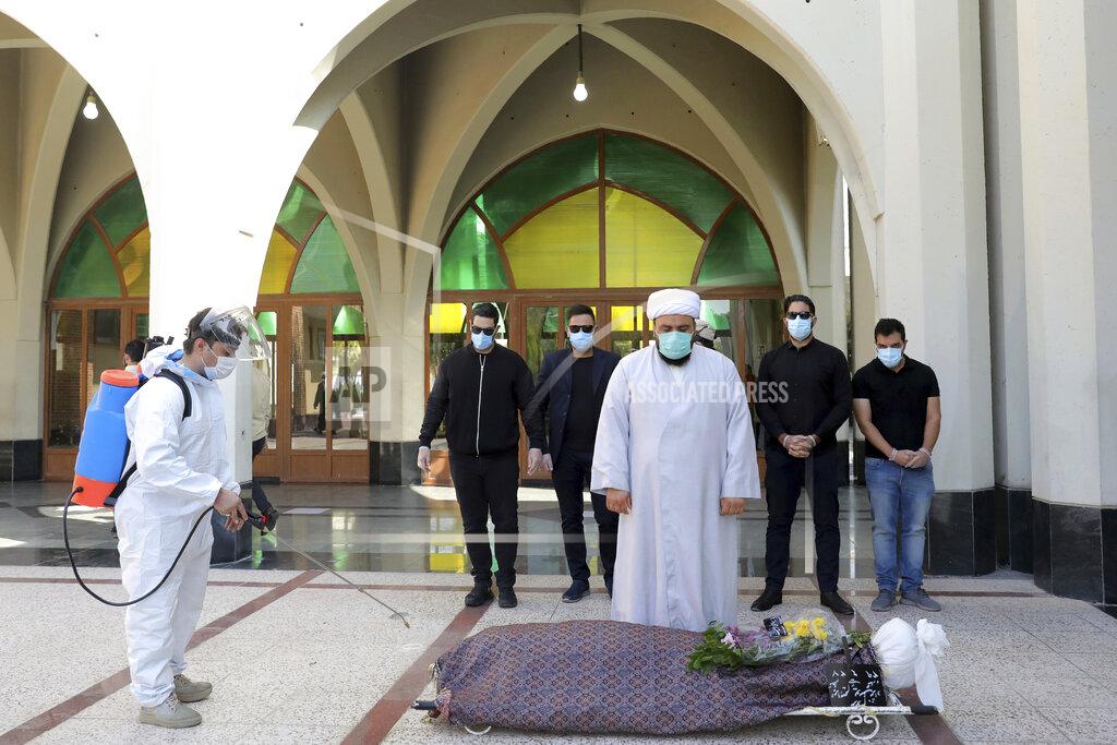 Ebrahim Noroozi A technician sprays disinfectant as mourners pray over the body of a person who died from COVID-19, at the Behesht-e-Zahra cemetery on the outskirts of the Iranian capital, Tehran, Iran, Sunday, Nov. 1, 2020. Behesht-e-Zahra, or "Zahra's Paradise" in Farsi, was named after a daughter of the Prophet Muhammad. (AP Photo/Ebrahim Noroozi)