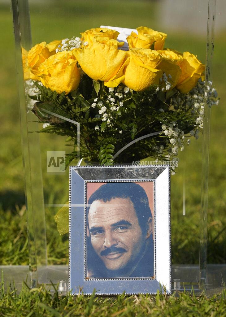 Chris Pizzello A portrait of the late actor Burt Reynolds sits in front of flowers during a ceremony featuring the unveiling of a memorial sculpture of Reynolds at Hollywood Forever Cemetery, Monday, Sept. 20, 2021, in Los Angeles. Reynolds died in 2018 at the age of 82. (AP Photo/Chris Pizzello)