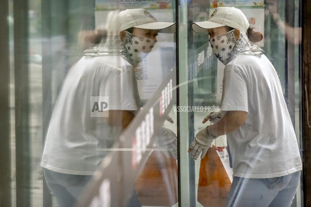 Mark Schiefelbein A delivery courier wearing a face mask to protect against COVID-19 is reflected in a window glass as she walks into a restaurant in Beijing, Tuesday, July 27, 2021. (AP Photo/Mark Schiefelbein)