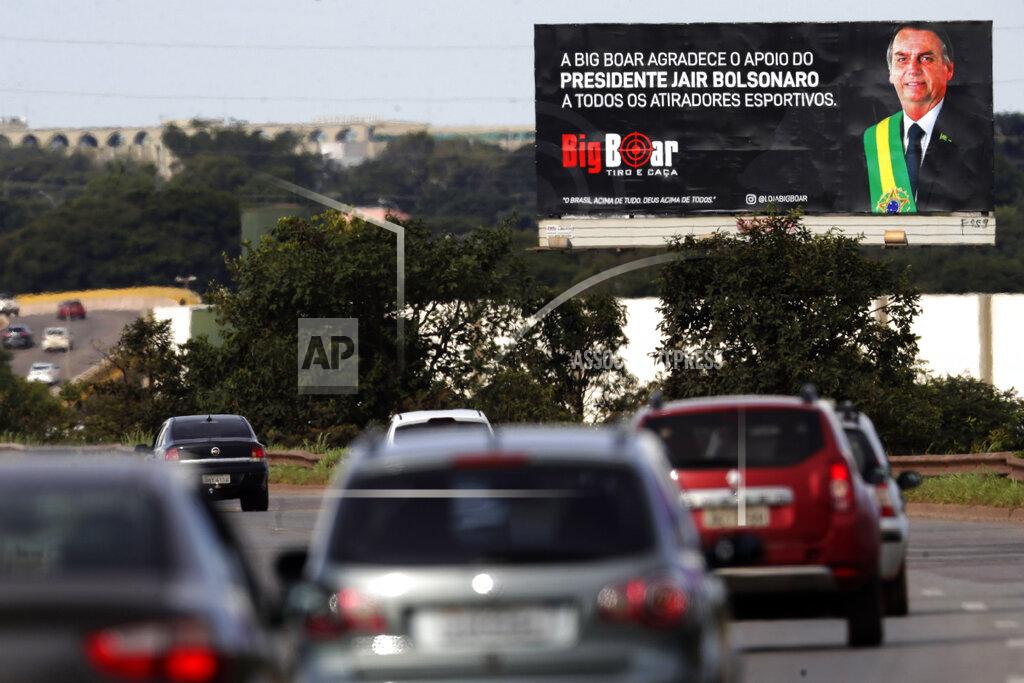 Eraldo Peres A billboard towering over traffic on an access road promotes the Big Boar gun shop plastered with an image of Brazil's President Jair Bolsonaro and a message that reads in Portuguese: "Big Boar thanks President Jair Bolsonaro for his support of all shooters," in Brasilia, Brazil, Friday, March 5, 2021. Bolsonaro is pushing to deliver on his promise to arm every person that wants it. (AP Photo/Eraldo Peres)