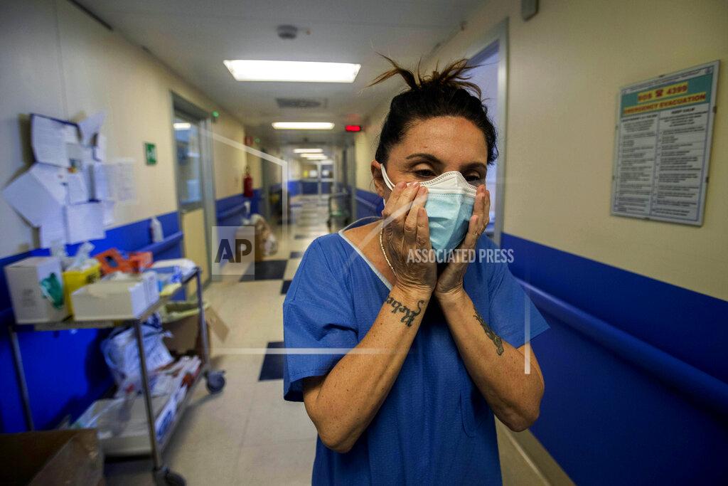 Luca Bruno Nurse Cristina Settembrese fixes two masks to her face during her work shift in the COVID-19 ward at the San Paolo hospital in Milan, Italy, April 10, 2020. Settembrese spends her days caring for COVID-19 patients in a hospital ward, and when she goes home, her personal isolation begins by her own choice. (AP Photo/Luca Bruno)