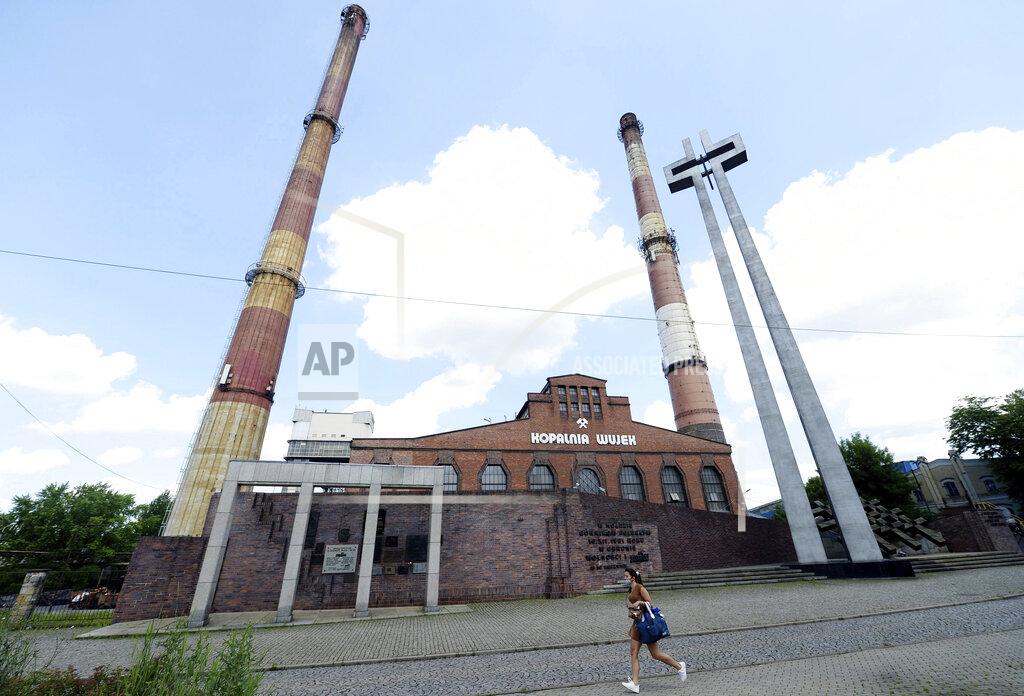 Czarek Sokolowski A woman walks by the closed Wujek coal mine in Katowice, Poland, Saturday, July 4, 2020. The coronavirus has ripped through Poland's coal mines, where men descend deep underground in tightly packed elevators and work shoulder-to-shoulder. The virus hot spots, centered in the southern Silesia region, have paralyzed an already-troubled industry, forcing many to stay home from work and triggering a three-week closure of many state-run mines. (AP Photo/Czarek Sokolowski)