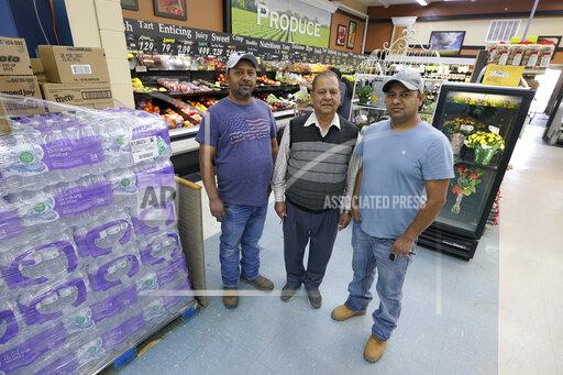 Singh Maan, center, poses for a photo with his sons CJ Maan, left, and Ricky Maan, right, Monday, Sept. 27, 2021, in the grocery store they own in Chester, Mont., near the scene where an Amtrak train derailed Saturday, killing three people and injuring others. When the crash happened, the family rushed to the scene with first-aid and food supplies taken right from the shelves of their store. (AP Photo/Ted S. Warren)