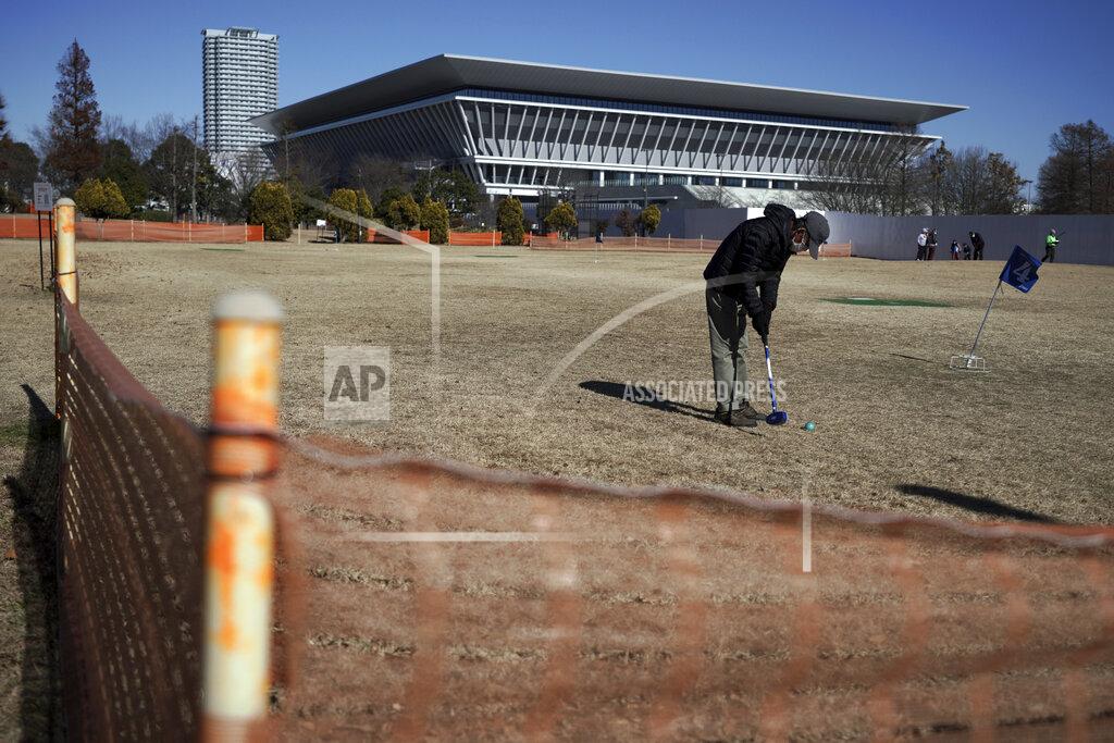 Eugene Hoshiko A man wearing a protective mask to help curb the spread of the coronavirus plays ground golf near the Tokyo Aquatics Center, one of the venues of Tokyo 2020 Olympic and Paralympic games, in Tokyo Wednesday, Jan. 20, 2021. The postponed Tokyo Olympics are to open in just six months. Local organizers and the International Olympic Committee say they will go ahead on July 23. But it’s still unclear how this will happen with virus cases surging in Tokyo and elsewhere around the globe. (AP Photo/Eugene Hoshiko)