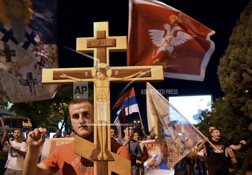 Risto Bozovic An opposition supporter holds a cross during church-led protest in Podgorica, Montenegro, Thursday, Aug. 27, 2020. Montenegro is holding a parliamentary election this weekend with the pro-Western government facing pressure over the new coronavirus outbreak and ongoing tensions in relations with Serbia and the Serbian Orthodox Church because of a religious property law. (AP Photo/Risto Bozovic)
