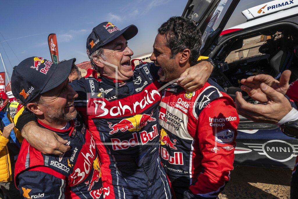 Bernat Armangue Driver Carlos Sainz, of Spain, center, is congratulated by Driver Stephane Peterhansel, of France, left, and driver Nasser Al-Attiyah, of Qatar, right, at the end of stage twelve of the Dakar Rally between Haradth and Qiddiya, Saudi Arabia, Friday, Jan. 17, 2020. (AP Photo/Bernat Armangue)