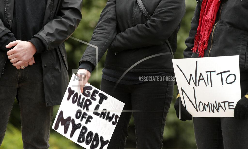 Barbara J. Perenic Several people dressed in black stood on the west side of the Ohio Statehouse in Columbus on Sunday, Oct. 25, 2020, to protest the confirmation of conservative judge Amy Coney Barrett to the Supreme Court while affirming women's rights including body autonomy. (Barbara J. Perenic/The Columbus Dispatch via AP)