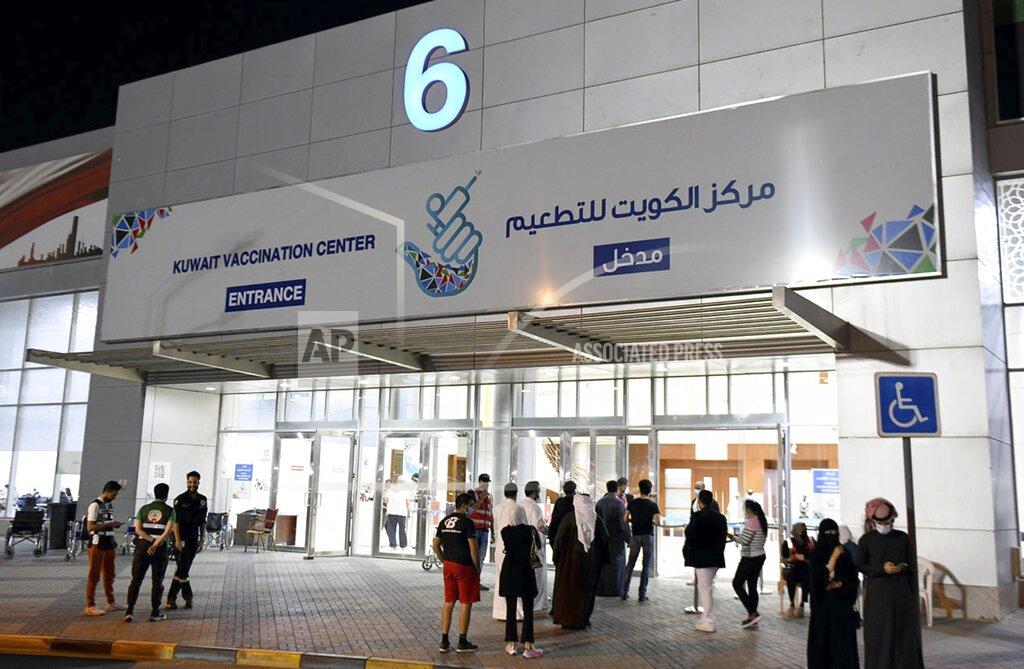 In this Friday, March 12, 2021 photo released by Kuwait News Agency, KUNA, people enter Kuwait Vaccination Centre to get the vaccine in Kuwait. In the tiny, oil-rich sheikhdom of Kuwait, the foreigners who power the country's economy, serve its society and make up 70% of its population are struggling to get COVID-19 vaccines. (KUNA via AP)