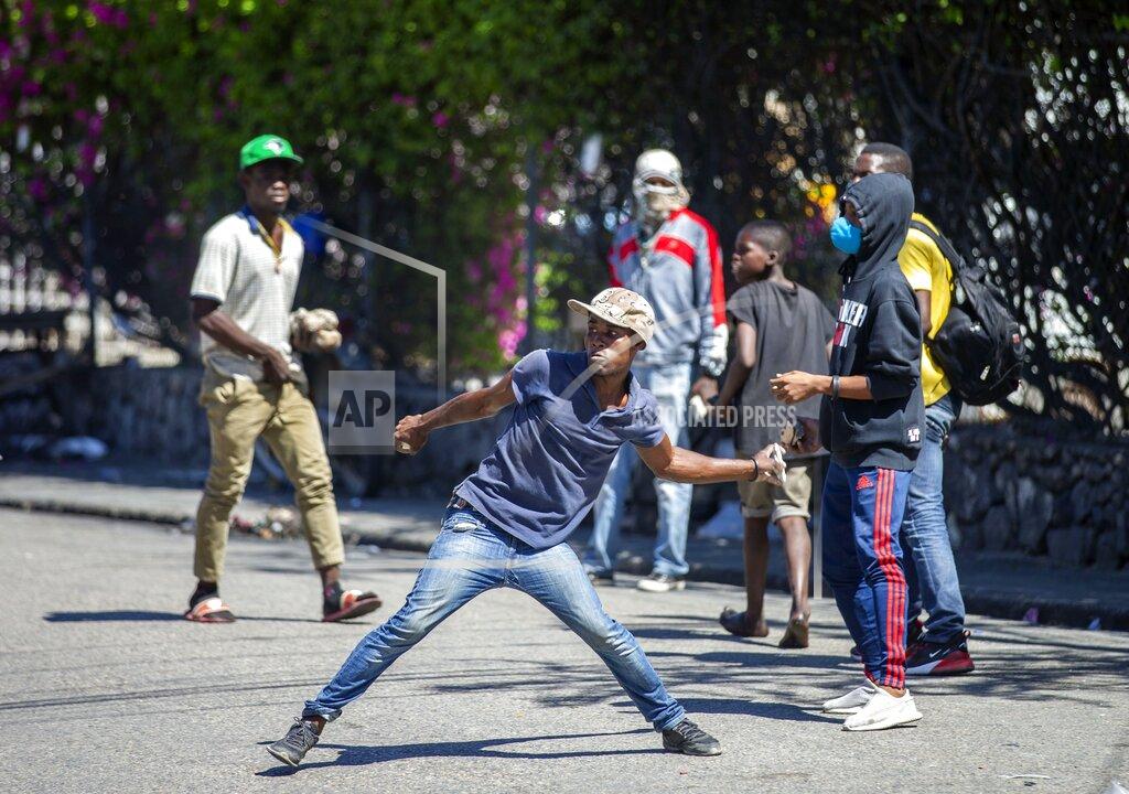 Dieu Nalio Chery A demonstrator throws rocks at the police during a protest to demand the resignation of Haitian President Jovenel Moise in Port-au-Prince, Haiti, Sunday, Feb. 7, 2021. ( AP Photo/Dieu Nalio Chery)