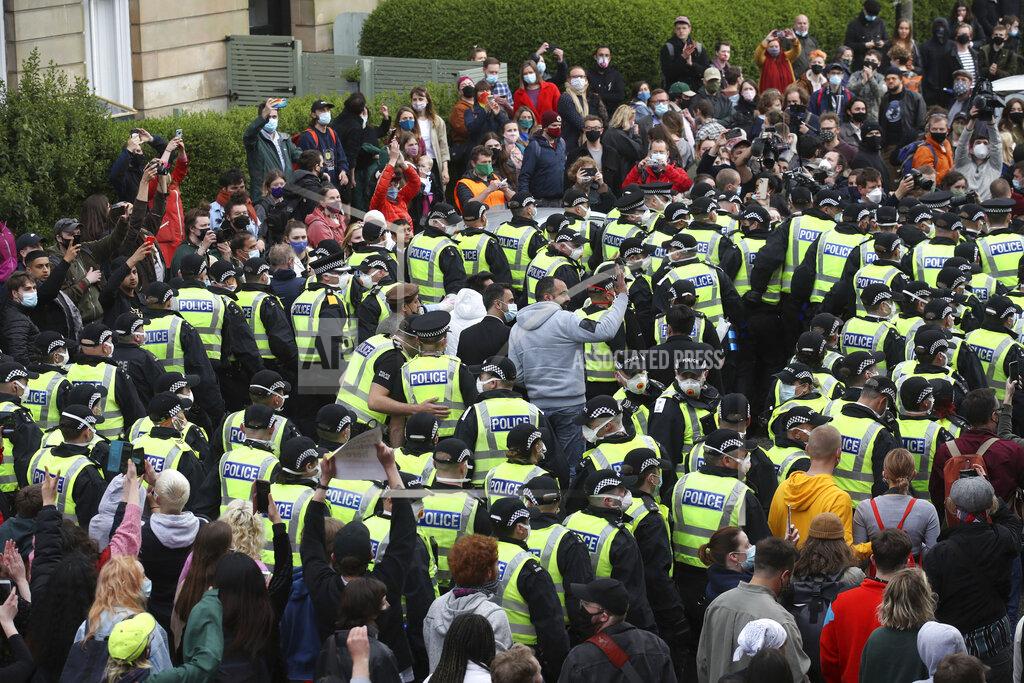 Andrew Milligan Two men stand surrounded by police and protesters, after being released from an Immigration Enforcement police van accompanied by lawyer Aamer Anwar and Mohammad Asif, director of the Afghan Human Rights Foundation, in Glasgow, Scotland, Thursday May 13, 2021. Some hundreds of protesters blockaded the street in Glasgow on Thursday in a seven-hour standoff which successfully forced the release of two men detained by U.K. immigration authorities. (Andrew Milligan/PA via AP)