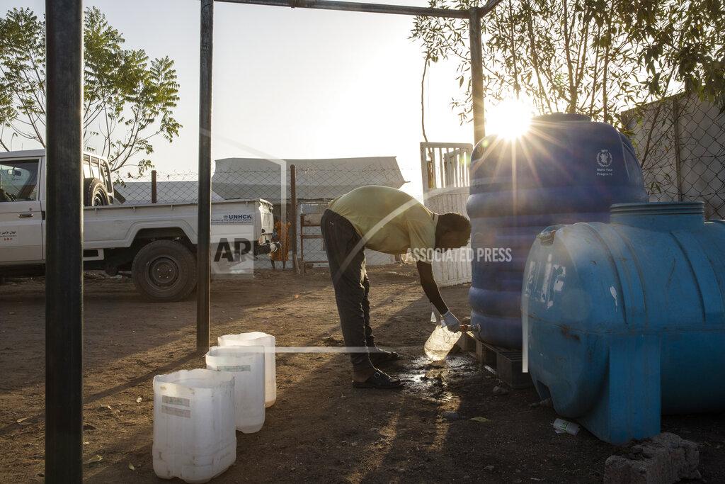 Nariman El-Mofty Surgeon and doctor-turned-refugee, Dr. Tewodros Tefera, fills a container with clean water to sanitize medical equipment, at the Sudanese Red Crescent clinic at the Hamdayet Transition Center near the Sudan-Ethiopia border, eastern Sudan, on March 22, 2021. With no running water or electricity, he and a handful of colleagues see well over 100 patients a day. (AP Photo/Nariman El-Mofty)