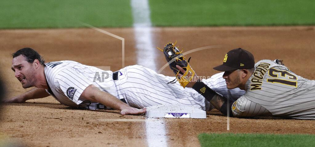 David Zalubowski San Diego Padres third baseman Manny Machado, right, holds up his glove to show that he tagged out Colorado Rockies' Daniel Murphy as he tries to advacnce from first to third base on a single hit by Ryan McMahon in the sixth inning of a baseball game Friday, July 31, 2020, in Denver. (AP Photo/David Zalubowski)