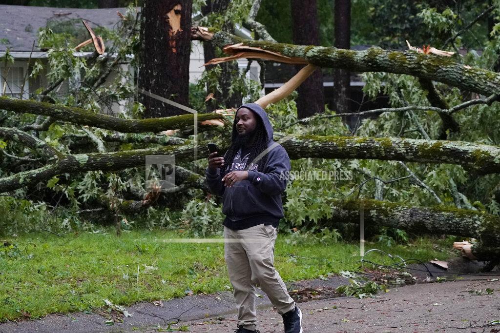 Rogelio V. Solis A northeast Jackson, Miss., resident talks with a friend on a phone as he inspects the wind toppled trees in his neighborhood, Tuesday, May 4, 2021. The severe weather was not unexpected, since the state was hit with a number of tornadoes on Sunday. (AP Photo/Rogelio V. Solis)