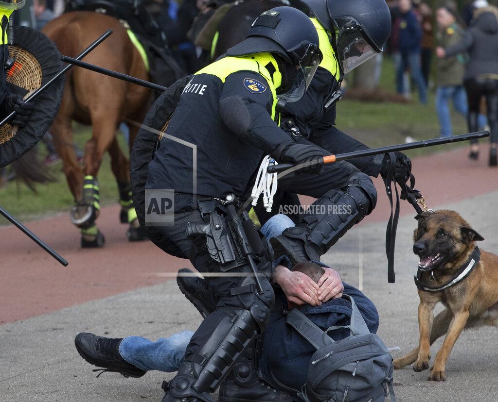 Peter Dejong Dutch riot police kick a man during a demonstration to protest government policies including the curfew, lockdown and coronavirus related restrictions in The Hague, Netherlands, Sunday, March 14, 2021. Thousands of people took part in the rally ahead of three days of voting starting Monday in a general election. (AP Photo/Peter Dejong)