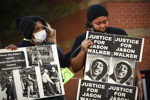 FILE - Pandora Harrington, right, cries as she holds a sign with an image of Jason Walker during a demonstration in front of the Fayetteville Police Department, Jan. 9, 2022, in Fayetteville, N.C. A judge has granted a North Carolina police chief's request to release body camera video recorded moments after last Saturday's fatal shooting of Walker by an off-duty sheriff’s deputy. The Fayetteville Observer reports that Senior Resident Superior Court Judge Jim Ammons issued his ruling Thursday, Jan. 13, 2022, two days after Fayetteville Police Chief Gina Hawkins filed the request. (Andrew Craft/The Fayetteville Observer via AP, File)
