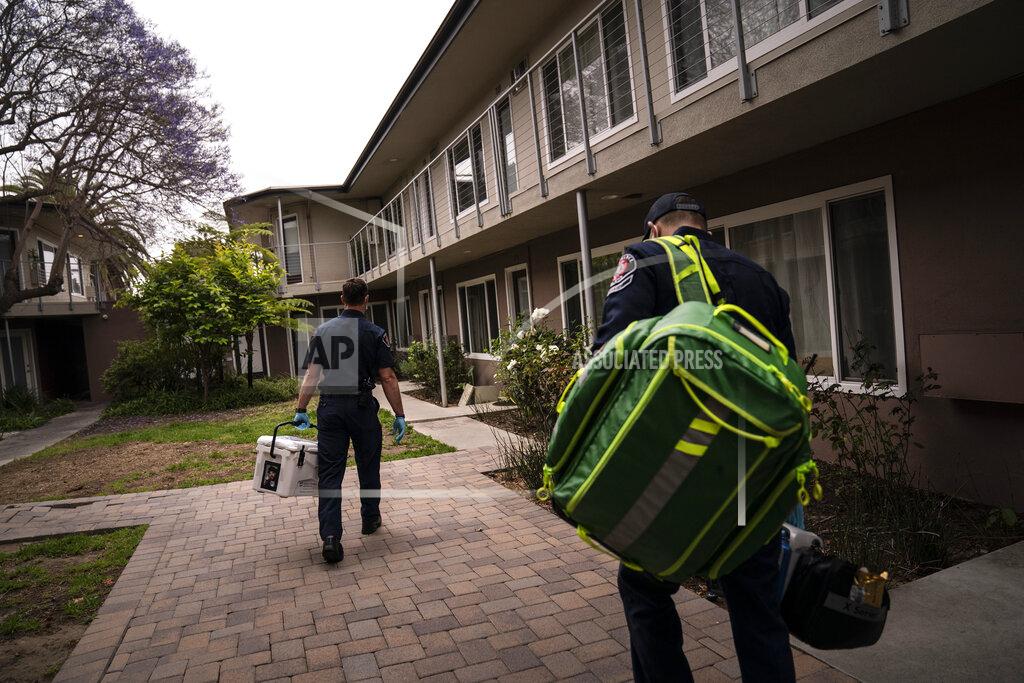 Jae C. Hong Torrance firefighters Trevor Borello, left, and Alessandro Demuro carry a cooler containing the Pfizer COVID-19 vaccine and medical equipment as they walk to an apartment to inoculate two sisters who have muscular dystrophy, Wednesday, May 12, 2021, in Torrance, Calif. Teamed up with the Torrance Fire Department, Torrance Memorial Medical Center started inoculating people at home in March, identifying people through a city hotline, county health department, senior centers and doctor's offices, said Mei Tsai, the pharmacist who coordinates the program. (AP Photo/Jae C. Hong)
