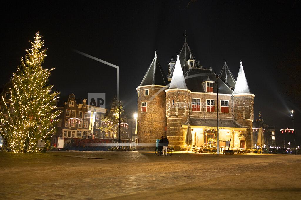 Peter Dejong FILE- In this Thursday Dec. 31, 2020, file photo, A couple kisses on the near-deserted Nieuwmarkt square in Amsterdam, Netherlands, Thursday, Dec. 31, 2020. The Dutch government said Wednesday, Jan. 20, 2021, that it wants to impose a curfew as part of beefed-up restrictions to rein in the spread of new more contagious variants of the coronavirus that already accounts for at least one in every 10 Dutch infections.(AP Photo/Peter Dejong, File)