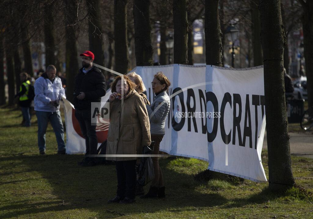 Peter Dejong A woman eats a sandwich during a demonstration ahead of three days of voting starting Monday in a general election, to protest government policies including the curfew, lockdown and coronavirus related restrictions in The Hague, Netherlands, Sunday, March 14, 2021. (AP Photo/Peter Dejong)