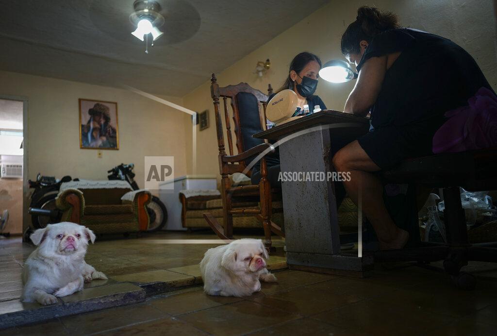 Ramon Espinosa Marylin Alvarez, right, prepares a client's nails in the salon at her home as her two dogs lounge on the floor, at the Bahía neighborhood of Havana, Cuba, Wednesday, May 18, 2022. During President Barack Obama's administration, Alvarez began transforming part of her house into a tiny cafe with the help of money sent by a cousin living in the U.S., but it fell apart when President Donald Trump's administration tightened the embargo and sharply restricted money transfers to Cuba in late 2020, which turned Alvarez to a less costly form of making money for her family — giving manicures. (AP Photo/Ramon Espinosa)