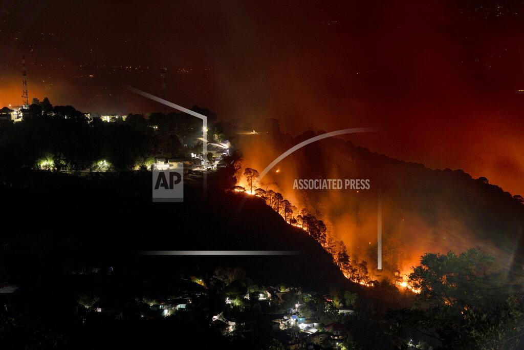 Ashwini Bhatia A forest on a mountain slope next to a township is seen on fire in Dharmsala, India, Monday, April, 25, 2022. The intense heat wave sweeping through South Asia was made more likely due to climate change and is a sign of things to come. An analysis by international scientists said that this heat wave was made 30 times more likely because of climate change and future warming would make heat waves more common and hotter in the future. Its effects have been cascading, ranging from forest fires and glacial floods to crop losses that forced India to ban exports on wheat. (AP Photo/Ashwini Bhatia, file)