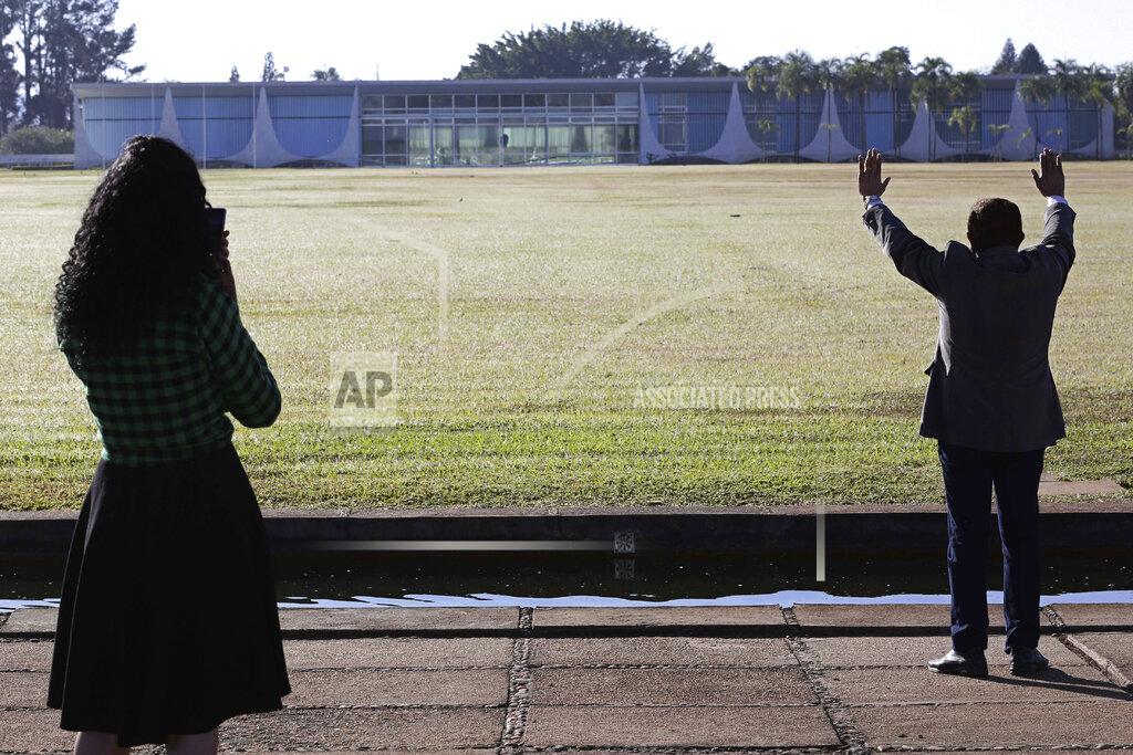 Eraldo Peres FILE - In this July 7, 2020 file photo, an evangelical pastor prays for Brazil's President Jair Bolsonaro, who said he tested positive for COVID-19, as a fellow evangelical stands with him outside the presidential residence Alvorada Palace in Brasilia, Brazil. Bolsonaro was not chastened by his own bout with COVID-19, and he kept touting hydroxychloroquine long after virtually all others ceased doing so. (AP Photo/Eraldo Peres, File)