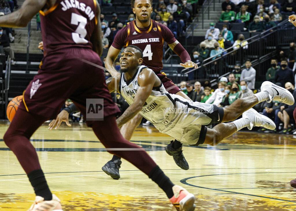 Thomas Boyd Oregon guard De'Vion Harmon, center, dives for the ball against Arizona State during an NCAA college basketball game in Eugene, Ore., Sunday, Dec. 5, 2021. (AP Photo/Thomas Boyd)
