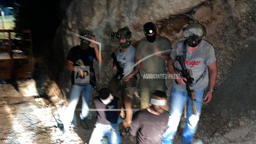 Uncredited In this photo provided by Israel Police, Israeli security forces stand next to two Palestinian fugitives Zakaria Zubeidi, left, and Mohammed Aradeh, blindfolded and handcuffed after being recaptured in the Arab town of Umm al-Ghanam, northern Israel, Saturday, Sept. 11, 2021. Israeli police on Saturday said they have arrested four of the six Palestinians who broke out of a maximum-security prison this week including Zubeidi, a famed militant leader whose exploits over the years have made him a well-known figure in Israel. (Israeli Police via AP)