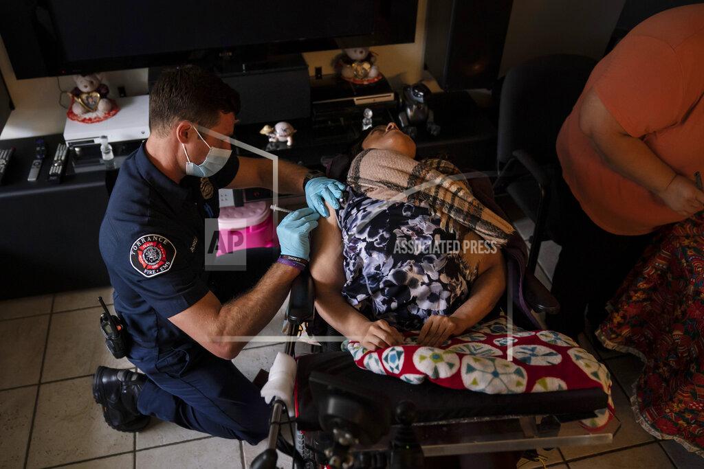 Jae C. Hong Torrance firefighter Trevor Borello, left, administers the second dose of the Pfizer COVID-19 vaccine to Barbara Franco, who has muscular dystrophy, at her apartment, Wednesday, May 12, 2021, in Torrance, Calif. Teamed up with the Torrance Fire Department, Torrance Memorial Medical Center started inoculating people at home in March, identifying people through a city hotline, county health department, senior centers and doctor's offices, said Mei Tsai, the pharmacist who coordinates the program. (AP Photo/Jae C. Hong)