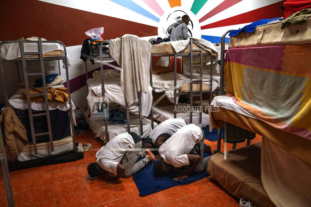 Emilio Morenatti Asylum-seekers pray next to their beds at the Modern Christian Mission Church in Fuerteventura, one of the Canary Islands, Spain, on Saturday, Aug. 22, 2020. The Modern Christian Mission is the main shelter for rescued migrants on the island of Fuerteventura. (AP Photo/Emilio Morenatti)
