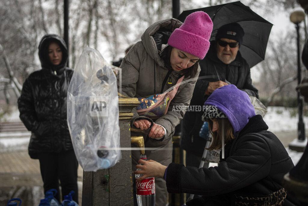 Evgeniy Maloletka People collect water, in Kyiv, Ukraine, Thursday, Nov. 24, 2022. Residents of Ukraine's bombed but undaunted capital clutched empty bottles in search of water and crowded into cafés for power and warmth Thursday, switching defiantly into survival mode after new Russian missile strikes a day earlier plunged the city and much of the country into the dark. (AP Photo/Evgeniy Maloletka)