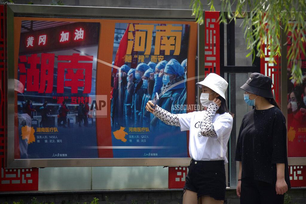 Mark Schiefelbein People wearing face masks to protect against the new coronavirus take photos near billboards honoring medical workers who responded to the coronavirus outbreak in Wuhan at a public park in Beijing, Friday, June 26, 2020. China reported a further decline in new cases Friday with about a dozen mostly in Beijing, where mass testing has been done following an outbreak that appears to have been largely brought under control. (AP Photo/Mark Schiefelbein)