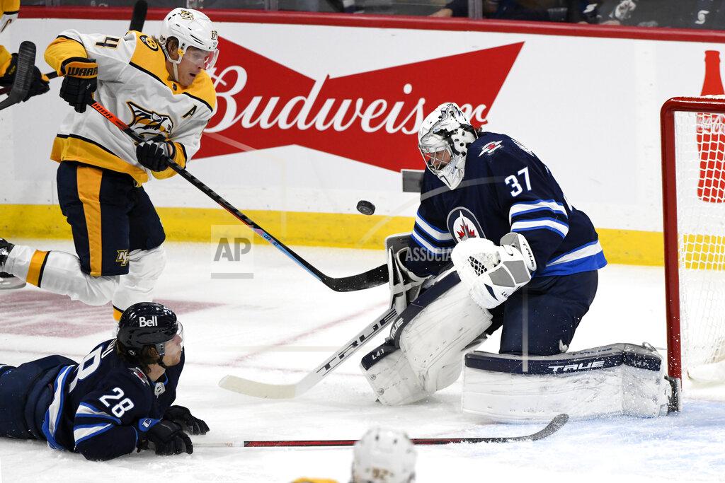 Fred Greenslade Winnipeg Jets goaltender Connor Hellebuyck (37) makes a save against Nashville Predators' Mikael Granlund (64) during the first period of NHL hockey game action in Winnipeg, Manitoba, Saturday, Oct. 23, 2021. (Fred Greenslade/The Canadian Press via AP)