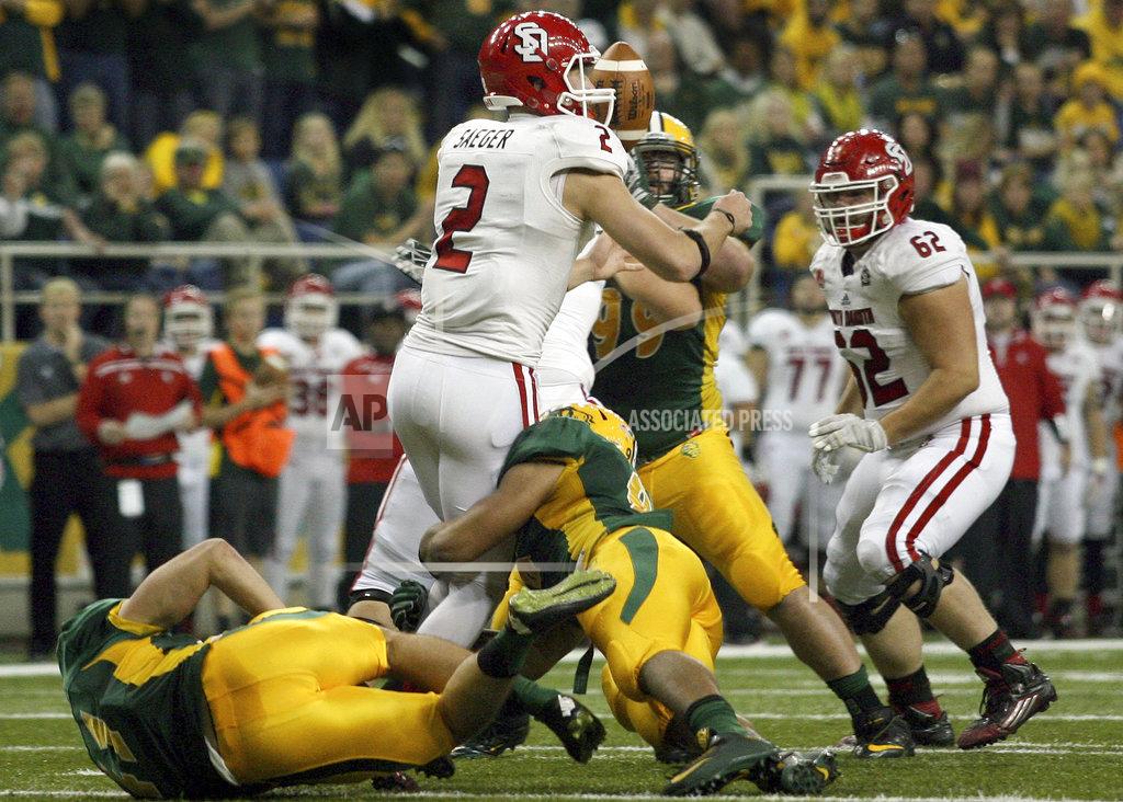 FILE - In this Oct. 17, 2015 file photo, the football pops out of South Dakota quarterback Ryan Saeger's hands on a first quarter sack by North Dakota State defenders, below, during an NCAA college football game in Fargo, N.D. South Dakota State has advanced to the Football Championship Subdivision semifinals for the second straight year and its reward is a matchup against powerful rivals North Dakota State. (AP Photo/Bruce Crummy, File)