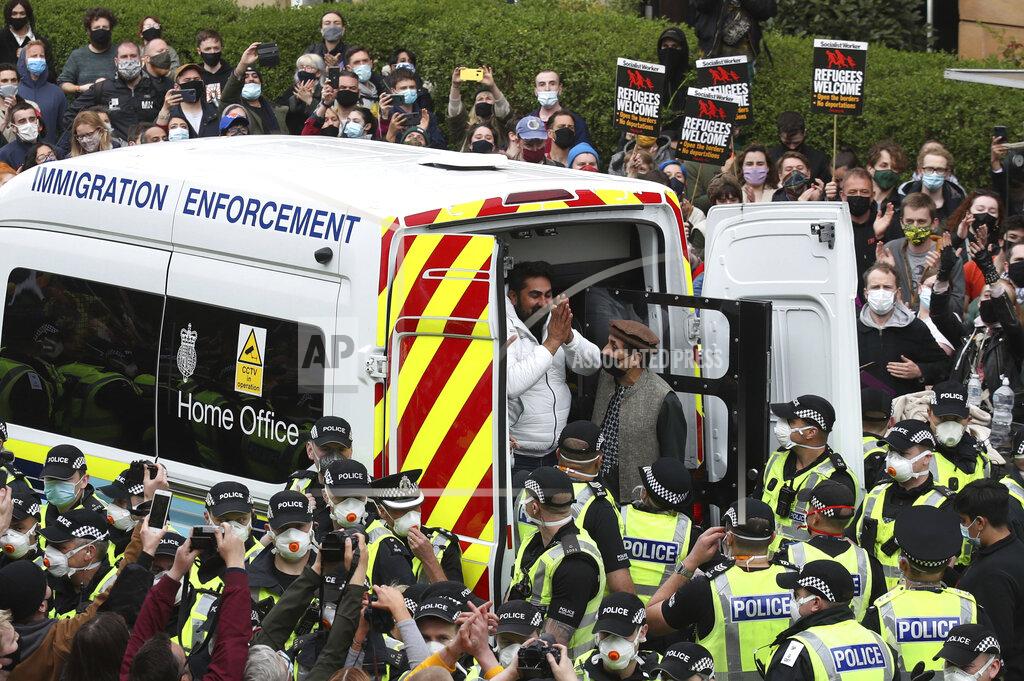 Andrew Milligan Two men are released from an Immigration Enforcement police van accompanied by Mohammad Asif, centre right, director of the Afghan Human Rights Foundation, in Glasgow, Scotland, Thursday May 13, 2021. Some hundreds of protesters blockaded the street in Glasgow on Thursday in a seven-hour standoff which successfully forced the release of two men detained by U.K. immigration authorities. (Andrew Milligan/PA via AP)