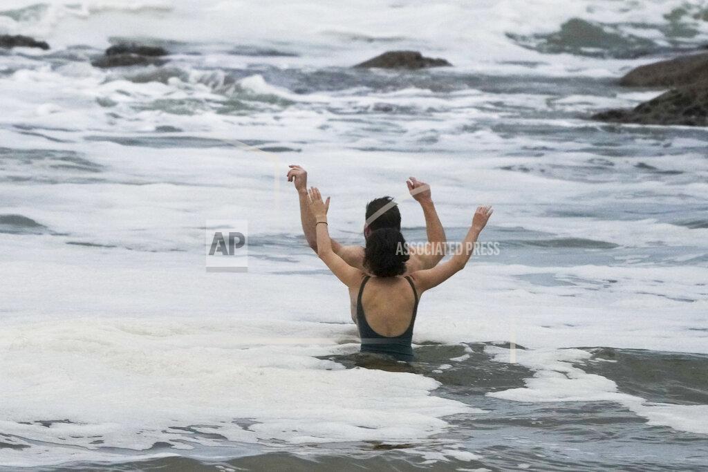 Mark Baker A couple react as they take a mid-winter swim at Bronte Beach as rain continues to fall in Sydney, Australia, Wednesday, July 6, 2022. More than 50,000 residents of Sydney and its surrounds have been told to evacuate or prepare to abandon their homes on Tuesday as Australia's largest city braces for what could be its worst flooding in 18 months. (AP Photo/Mark Baker)