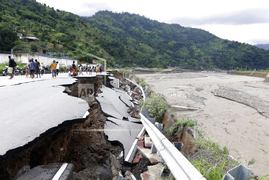 Kandhi Barnez Residents inspect a damaged road following a flood in Dili, East Timor, Monday, April 5, 2021. Multiple disasters caused by torrential rains in eastern Indonesia and neighboring East Timor have left a number of people dead or missing as rescuers were hampered by damaged bridges and roads and a lack of heavy equipment Monday. (AP Photo/Kandhi Barnez)
