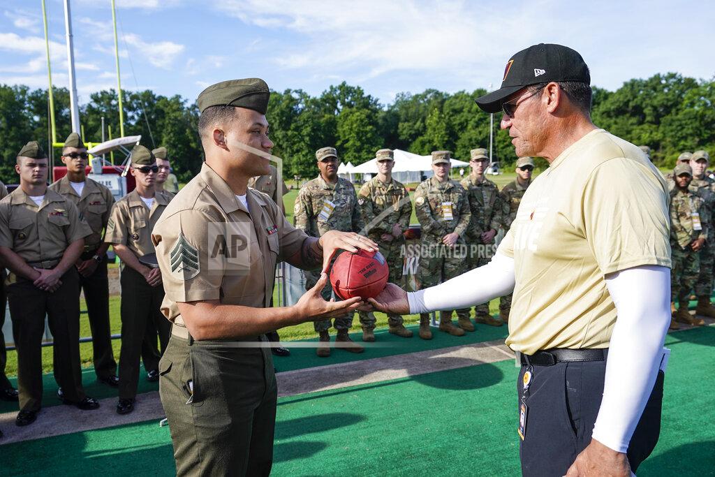 Alex Brandon U.S. Marine Corps Sgt. Dorian Roblin, with HMX-1, receives a game ball from Washington Commanders head coach Ron Rivera during a Salute to Service event before practice at the team's NFL football training facility, Saturday, July 30, 2022 in Ashburn, Va. (AP Photo/Alex Brandon)