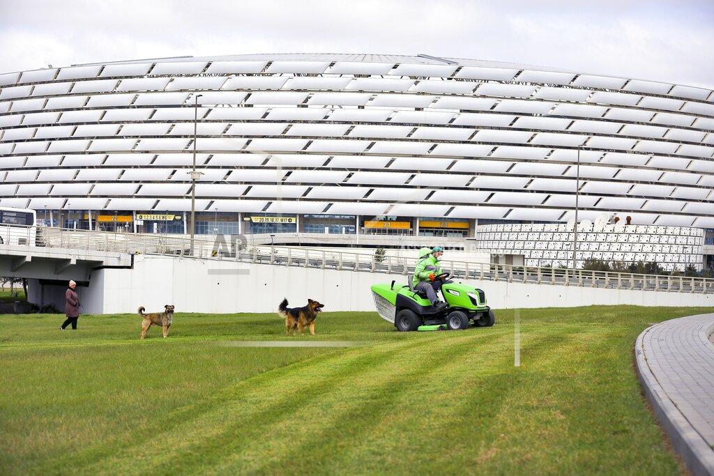 Aziz Karimov FILE - In this Wednesday, March 18, 2020 file photo, a worker rides a tractor as he mows a lawn in front of the Olympic stadium, in Baku, Azerbaijan. With coronavirus restrictions eased to allow fans back into stadiums, there at least will be some atmosphere at the tournament after months of games being played without any. Budapest wants all fans to come, while Saint Petersburg and Baku hope to use 50% of stadium capacity. (AP Photo/Aziz Karimov, File)