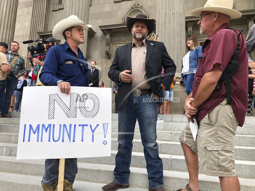Keith Ridler FILE - In this Monday, Aug. 24, 2020 file photo, Ammon Bundy, center, stands on the Idaho Statehouse steps in Boise, Idaho, to attend a special session of the state legislature called due to the coronavirus pandemic. Bundy, whose family led armed standoffs against federal agents in 2014 and 2016, has become an icon for paramilitary groups and right-wing extremists, most recently forming a multi-state network that has organized protests against public health measures. (AP Photo/Keith Ridler)