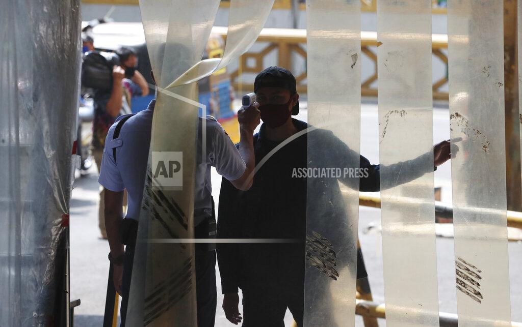 Achmad Ibrahim A security guard checks the body temperature of a men before entry a market, amid coronavirus outbreak in Jakarta, Indonesia Tuesday, June 30, 2020.(AP Photo/Achmad Ibrahim)